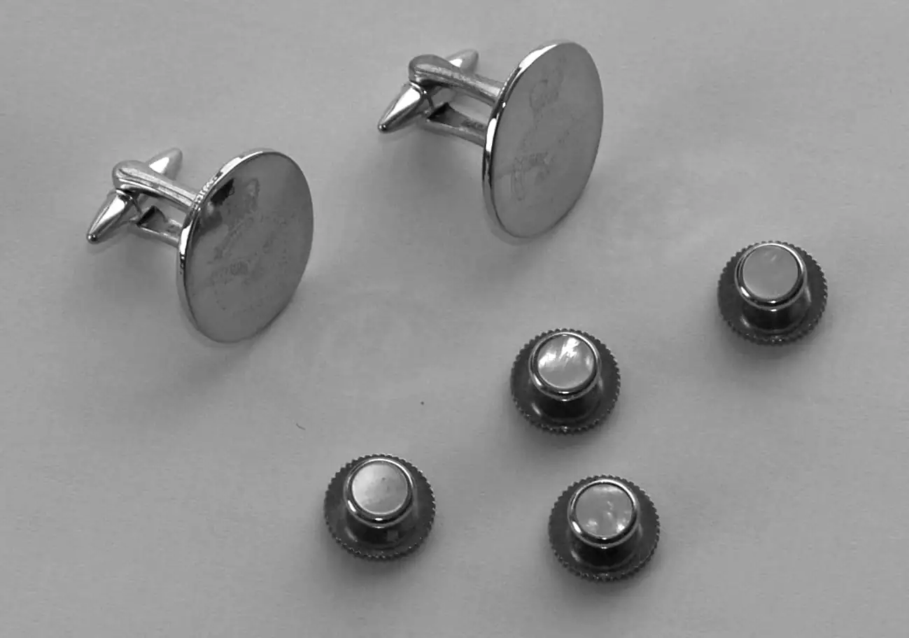 Black and white: cufflinks and dress-shirt studs laid out on linen