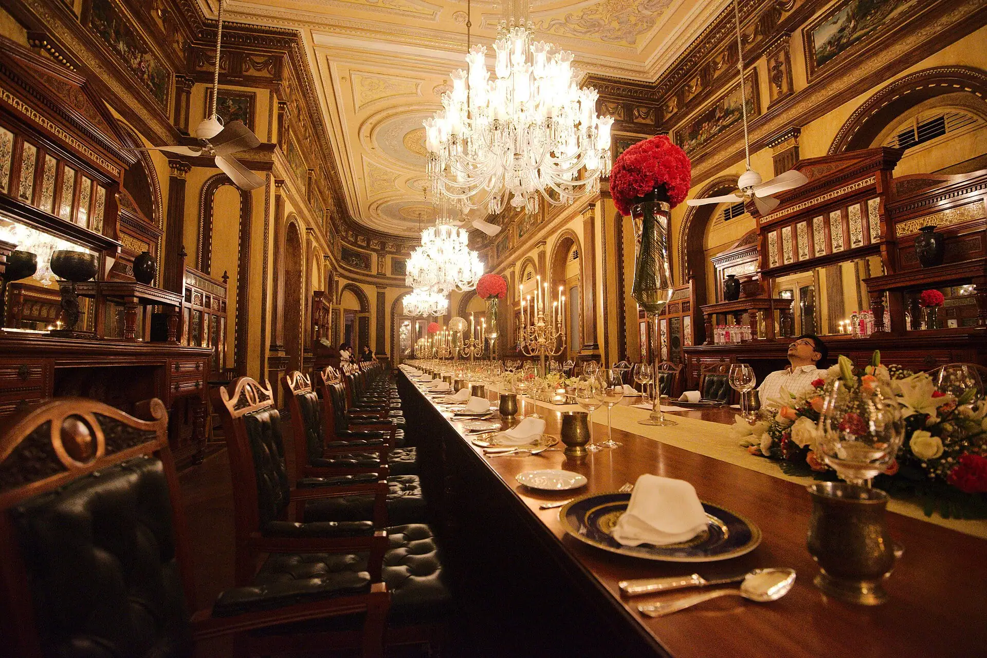 A long palace dining table set beneath crystal chandeliers