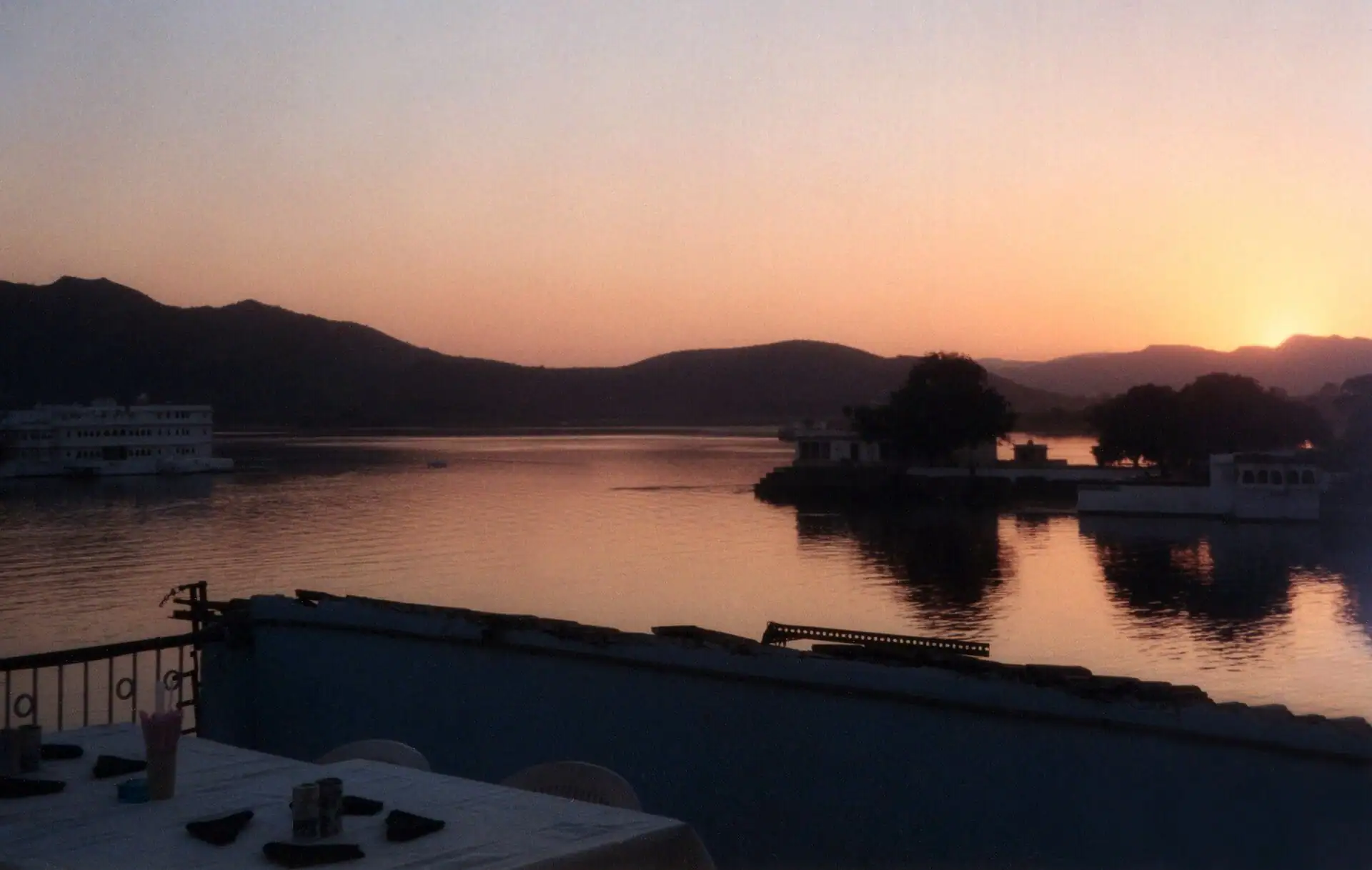 An island pavilion on Lake Pichola at dusk, the water gold and still