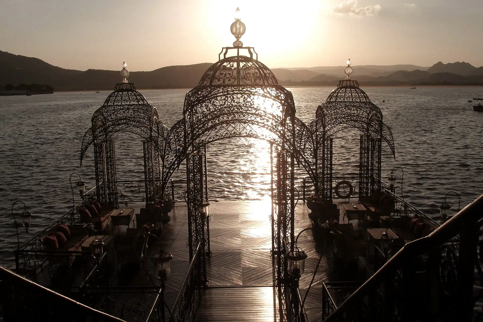 Filigree domes of a lakeside pavilion with the sun low behind them